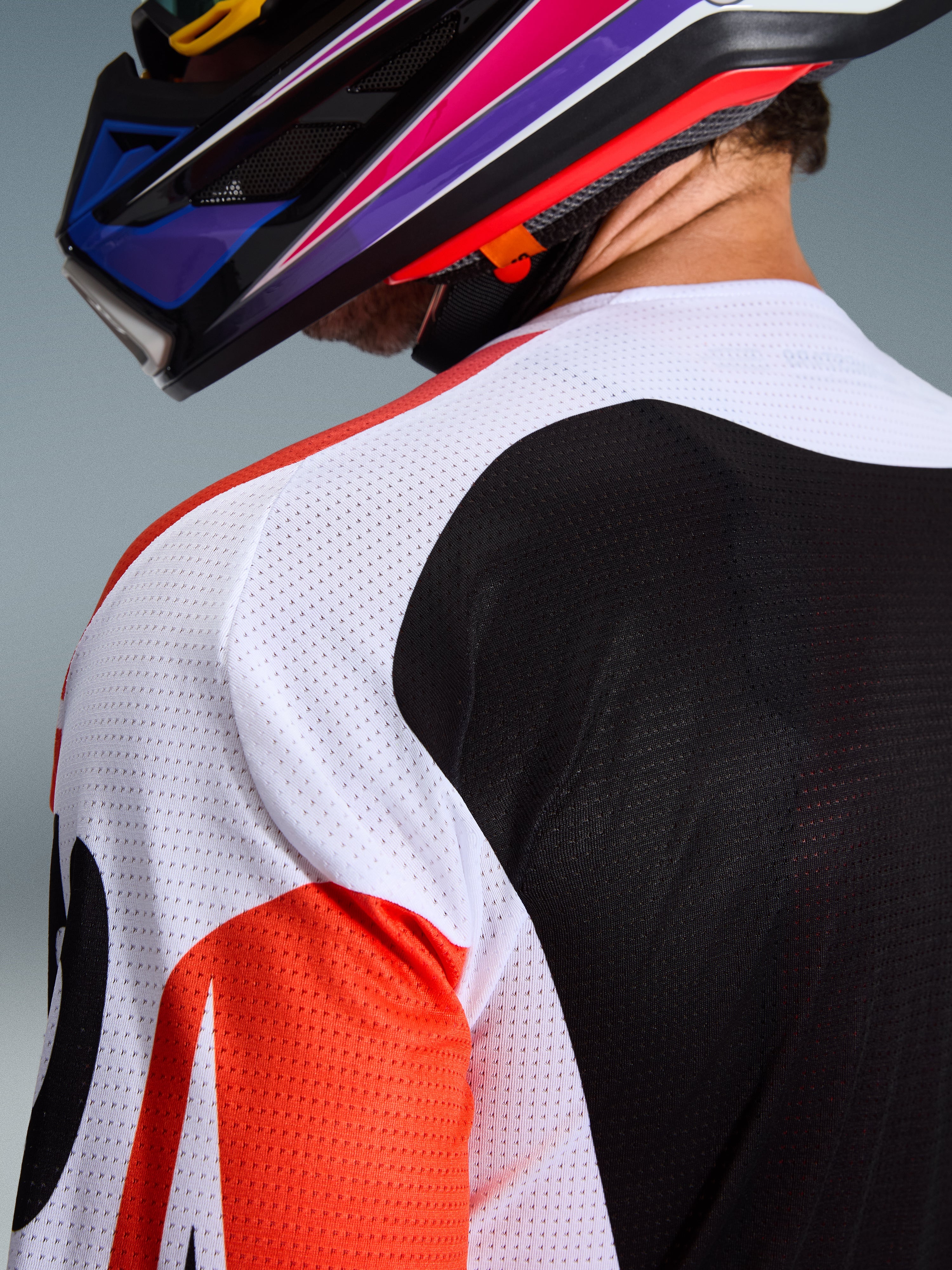 Alpinestars 2026 Racer Air Portl trøje, motocross-trøje, flerfarvet med hvide, sorte og røde paneler, nærbillede af den perforerede mesh-konstruktion på skulder og ryg for ventilation, båret med en farverig motocross-hjelm