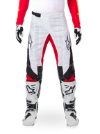 Alpinestars Limited Edition Techstar Deep bukser, motocross-bukser, hvid med sorte og røde accenter, med stjernelogo og laserperforeringer, båret med hvide motocross-støvler og handsker, holdbart teknisk materiale til terrænkørsel