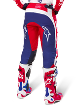 Alpinestars Limited Edition Techstar Fortitude bukser, motocross-bukser, rød, hvid og blå, set bagfra båret med matchende røde og hvide støvler, hvide stjernelogoer på lårene, holdbart multi-panel design til professionel off-road racing