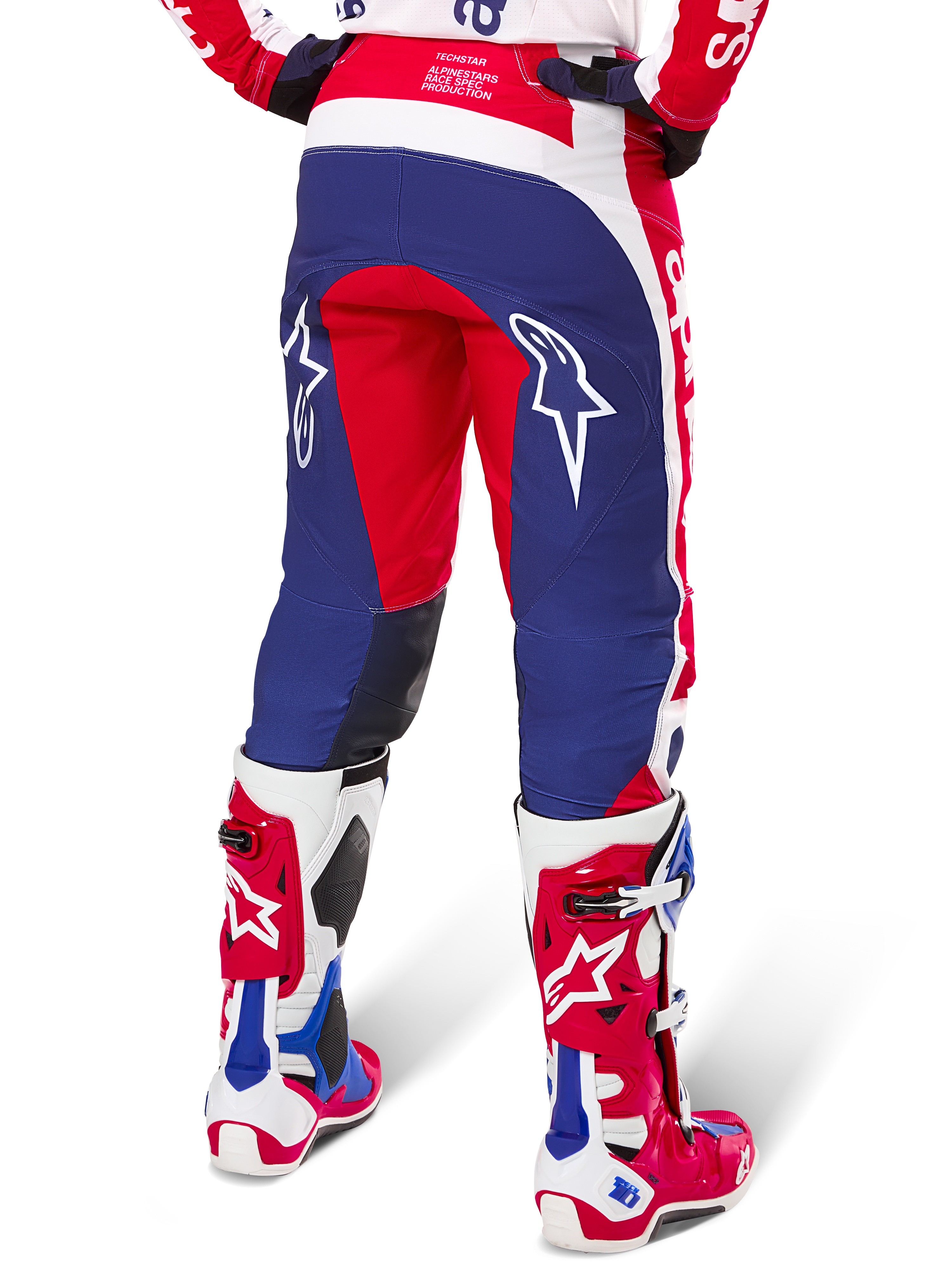 Alpinestars Limited Edition Techstar Fortitude bukser, motocross-bukser, rød, hvid og blå, set bagfra båret med matchende røde og hvide støvler, hvide stjernelogoer på lårene, holdbart multi-panel design til professionel off-road racing
