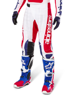 Alpinestars Limited Edition Techstar Fortitude bukser, motocross-bukser, rød, hvid og blå, båret med matchende off-road støvler og handsker, med lodret branding på benet, åndbare perforerede paneler og sorte forstærkede knæsektioner, atletisk racerdesign