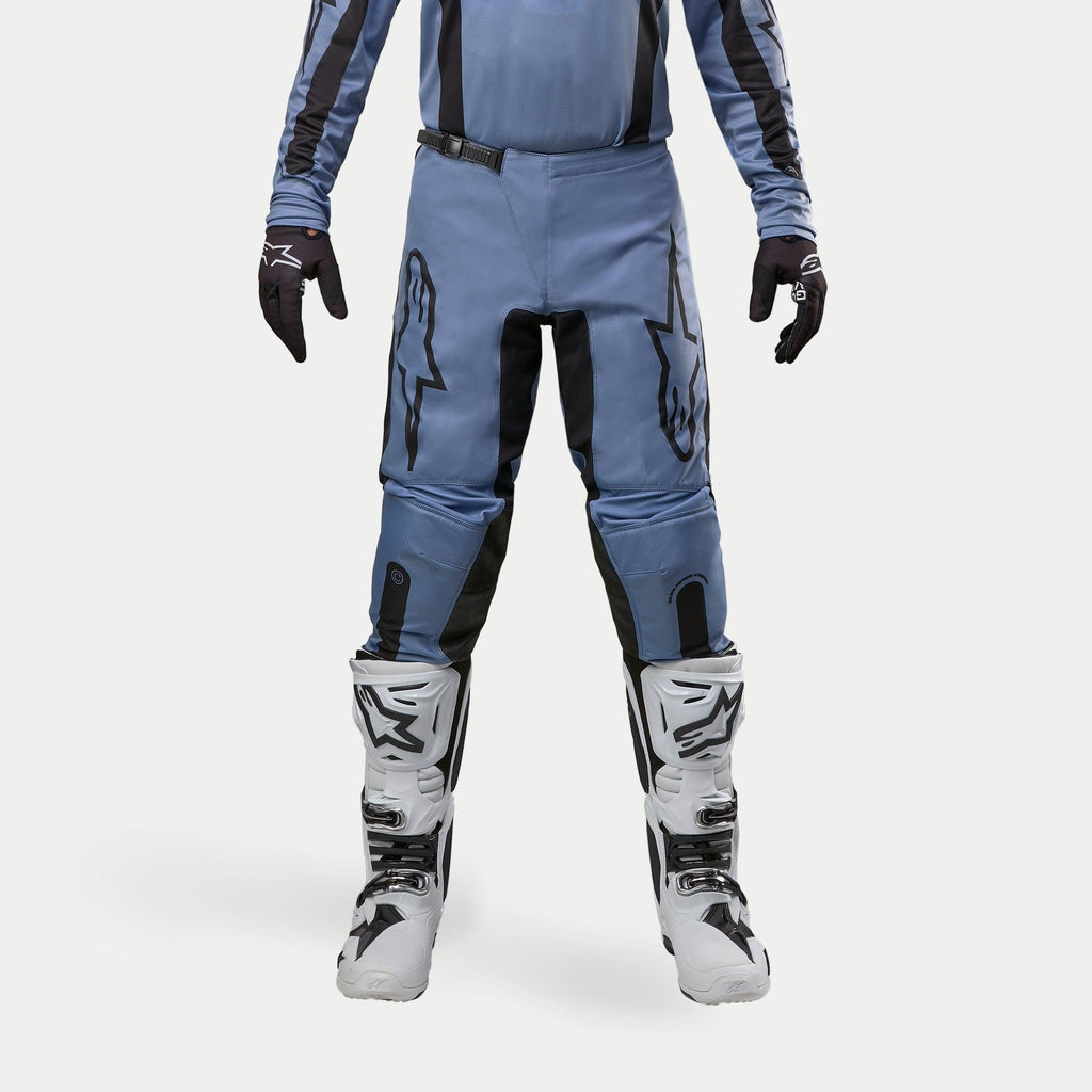 Alpinestars 2024 Fluid Lurv bukser, motocrossbukser, lyseblå og sort, vist med hvide og sorte racingstøvler og matchende handsker, med markante sorte stjernelogoer på lårene, ergonomisk design til off-road performance