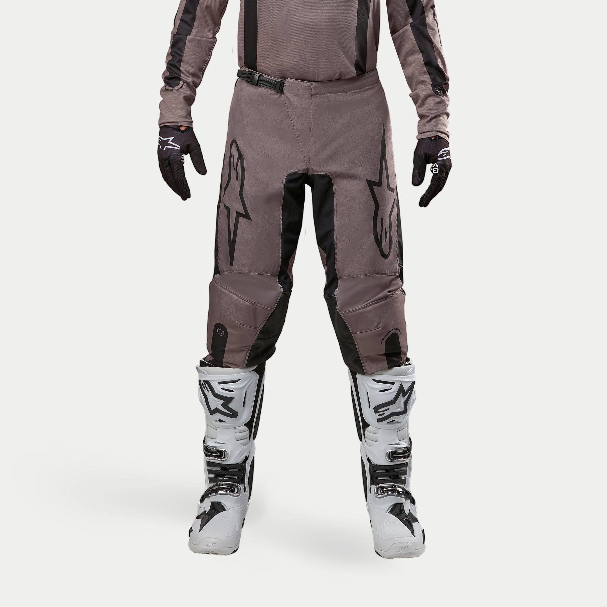 Alpinestars 2024 Fluid Lurv bukser, motocross-bukser, Mud Black, båret med matchende trøje, sorte handsker og hvide støvler, med store sorte logoer på lårene, ergonomisk pasform og slidstærkt materiale til off-road racing