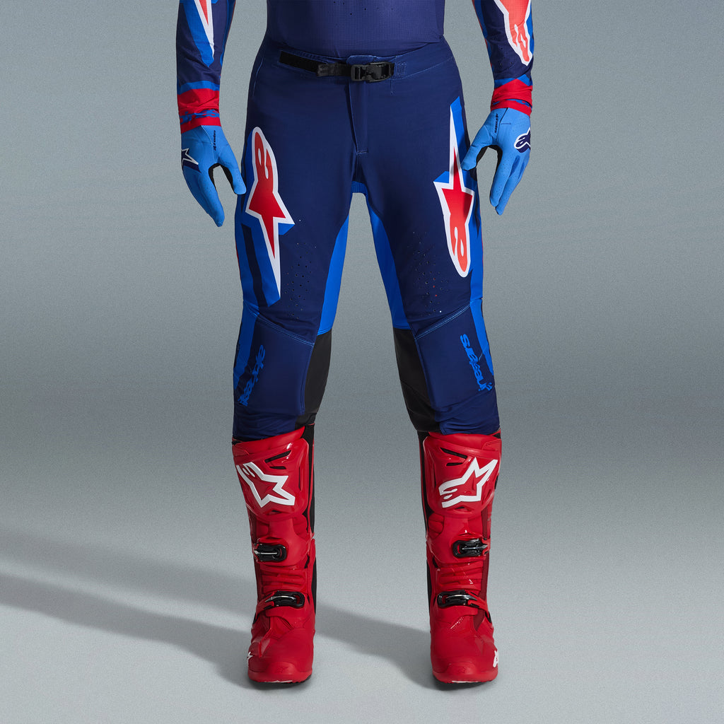 Alpinestars 2026 Supertech Vista udstyrssæt, motocrossbukser i navy og klar blå med røde og hvide logoer, kombineret med lyseblå handsker og klare røde motocrossstøvler, professionelt racerudstyr.