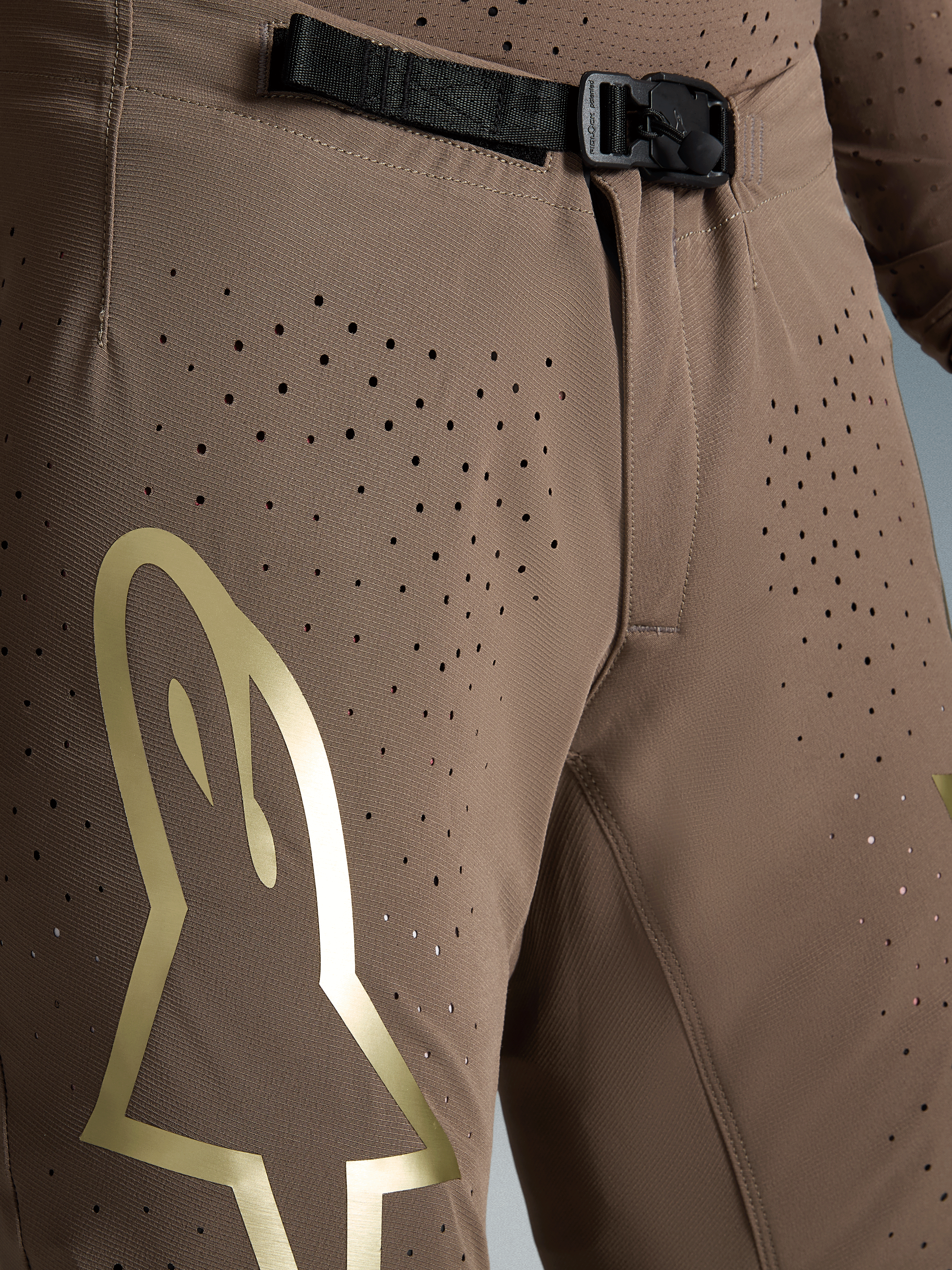 Alpinestars Begrænset Udgave Supertech Air Gold bukser, motocrossbukser i brun med guld Astars-logo, SX1 magnetisk spænde og perforeringer.