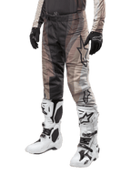 Alpinestars 2024 Techstar Pneuma bukser, motocross-bukser, mørk sand og jerngrå, båret med hvide og sorte støvler og sorte handsker, med et bølget mønster og stort stjernelogo, slidstærkt udstyr til terrænkørsel