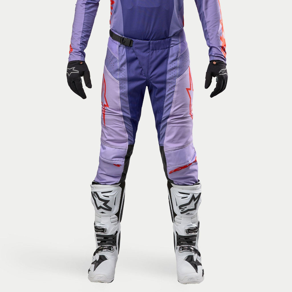 Alpinestars 2024 Techstar Ocuri bukser, motocross off-road bukser, lilla og neon orange med sorte detaljer, hvidt logo, magnetisk SX2-lukning, ventilationszoner, hvide støvler og sorte handsker, professionelt racerdesign
