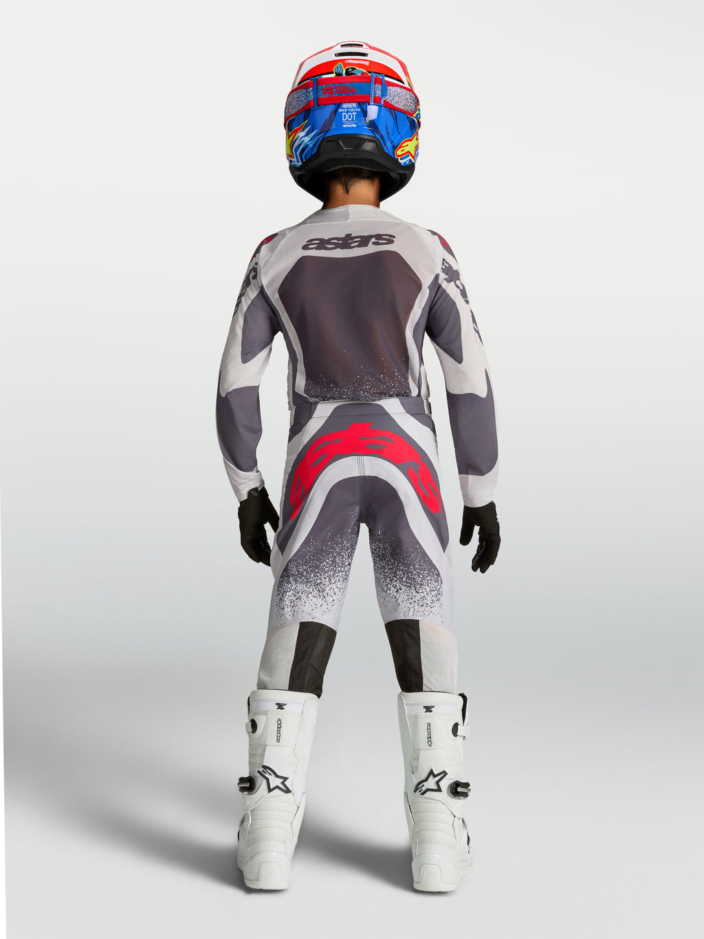 Alpinestars 2027 Supertech Swan bukser til unge, grå og rød fluo motocross-bukser set bagfra på en ung rytter.
