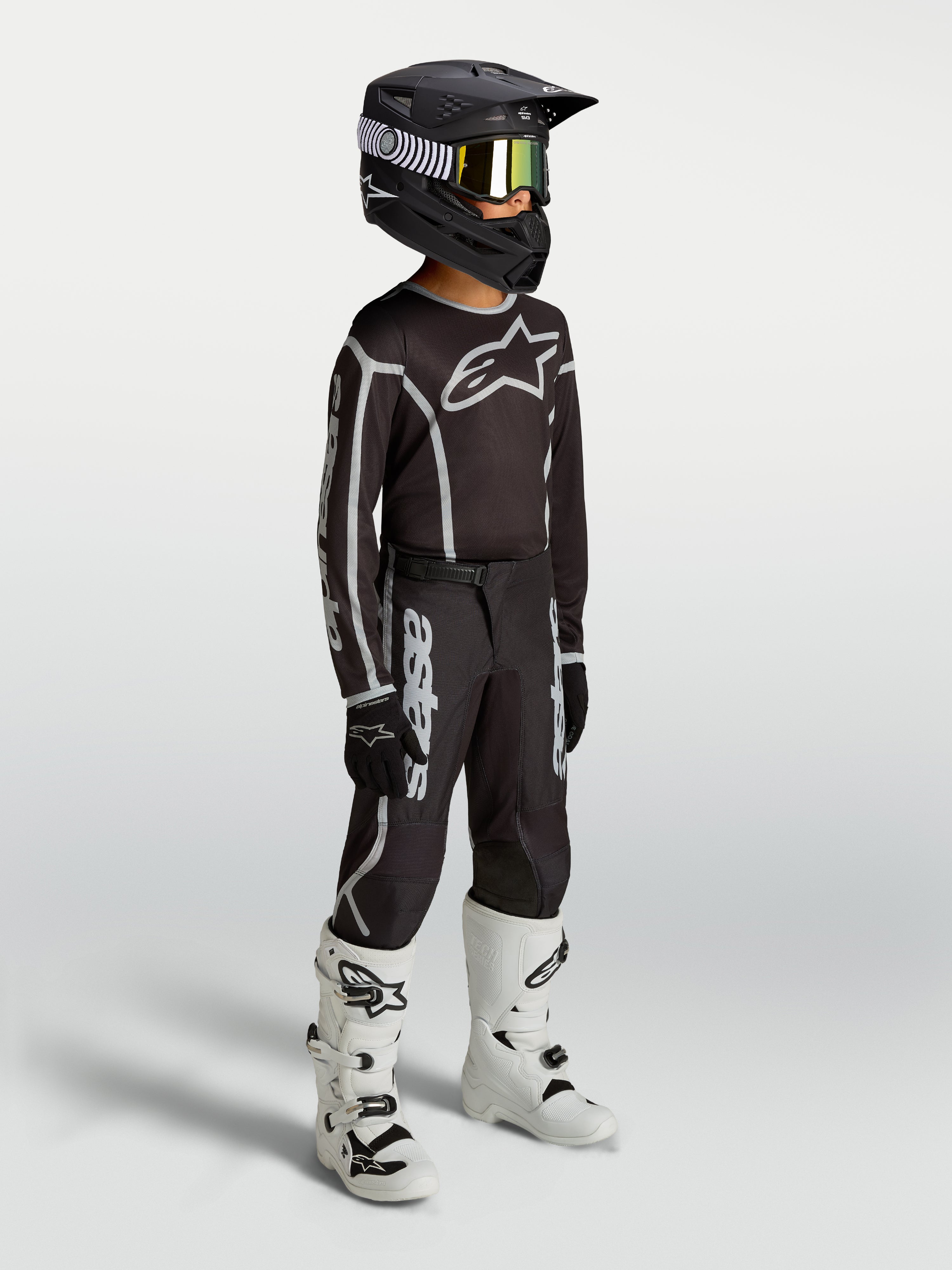 Alpinestars Youth Fluid Apex V2 Pants, black and silver motocross gear shown on-model with jersey, helmet, and white boots.