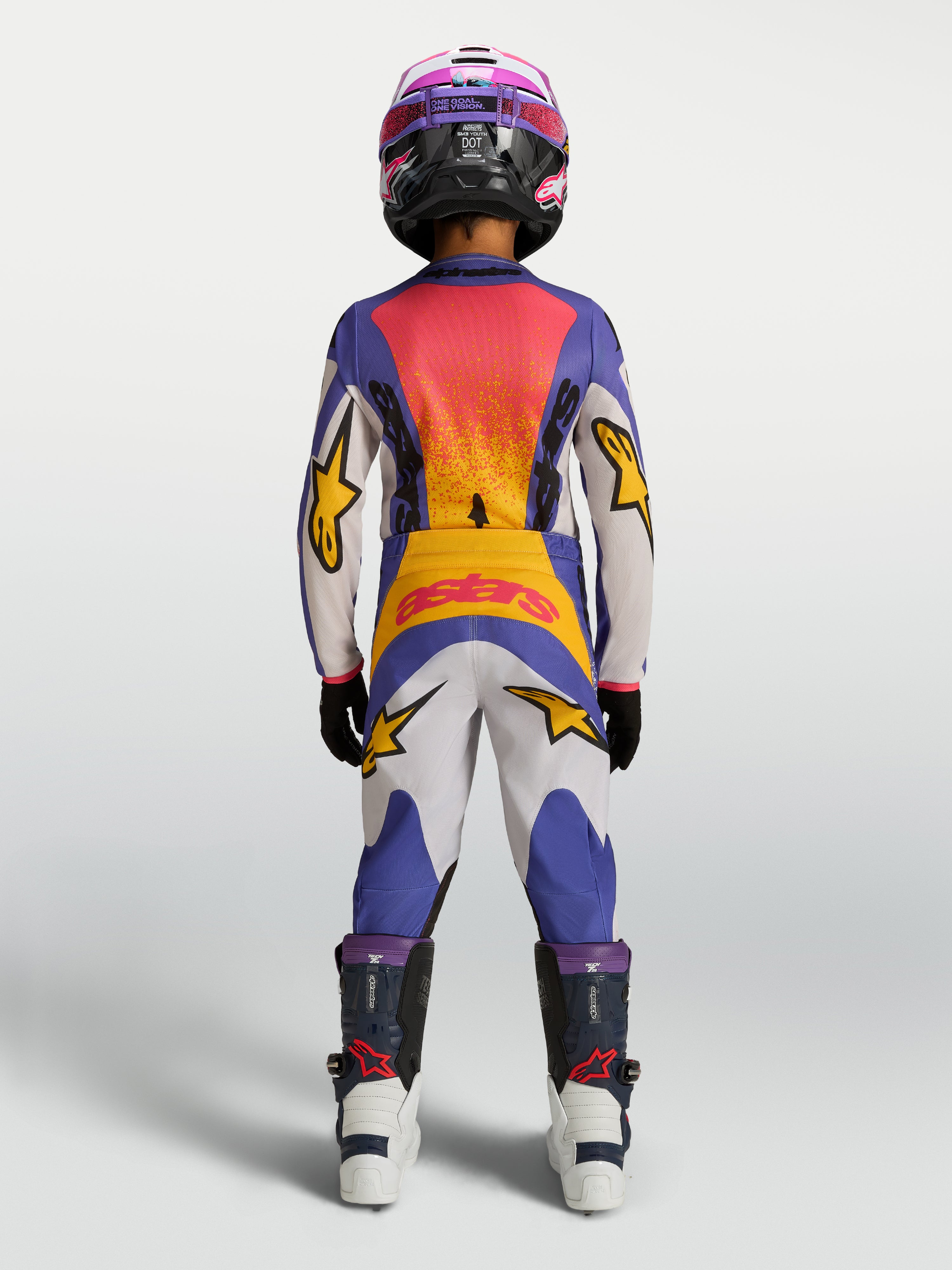 Alpinestars 2027 Fluid Drag bukser ungdom, tekniske motorcykelbukser til motocross og off-road kørsel, blå og hvid med gule detaljer, vist bagfra på en ung rytter i fuldt udstyr