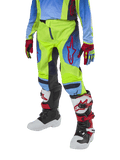 Alpinestars Youth 2024 Racer Hoen bukser, motocross-bukser til unge, neongul og mørkeblå med røde detaljer, båret med matchende handsker og hvide, sorte og røde støvler, med sportspasform og forbuede ben til terrænkørsel