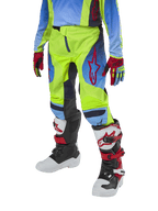 Alpinestars Youth 2024 Racer Hoen bukser, motocross-bukser til unge, neongul og mørkeblå med røde detaljer, båret med matchende handsker og hvide, sorte og røde støvler, med sportspasform og forbuede ben til terrænkørsel