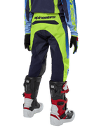 Alpinestars 2024 Youth Racer Hoen bukser, motocrossbukser, gul fluo og mørkeblå, set bagfra med tydeligt Alpinestars-branding på linningen, båret med sorte og røde Tech Series-støvler og matchende trøje, holdbar sportspasform til off-road kørsel for unge.