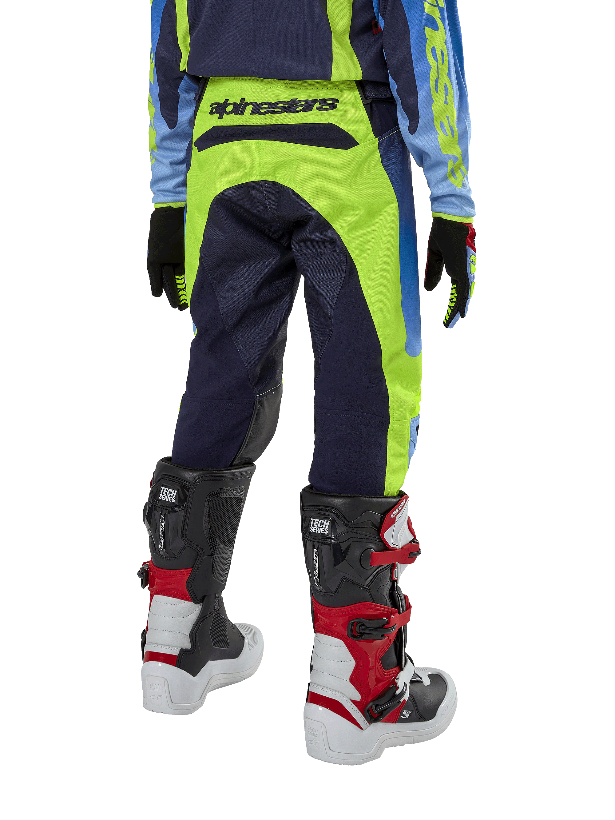Alpinestars 2024 Youth Racer Hoen bukser, motocrossbukser, gul fluo og mørkeblå, set bagfra med tydeligt Alpinestars-branding på linningen, båret med sorte og røde Tech Series-støvler og matchende trøje, holdbar sportspasform til off-road kørsel for unge.
