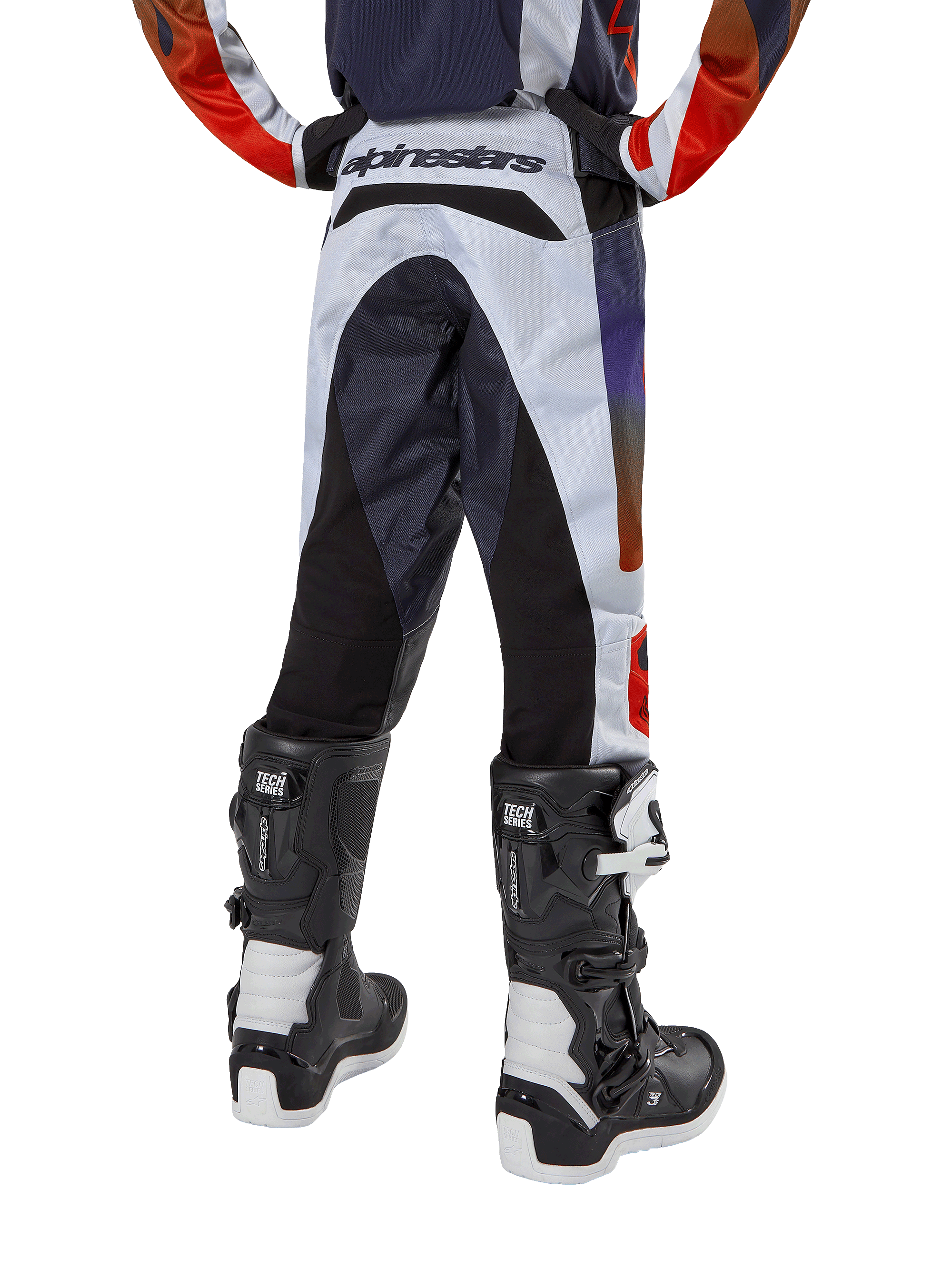 Alpinestars 2024 Youth Racer Hoen bukser, motocrossbukser til unge, lysegrå med stærk orange og sorte detaljer, set bagfra med sorte paneler på sædet og benene, markant branding på bagtaljen, båret med sort-hvide motocrossstøvler til terrænkørsel