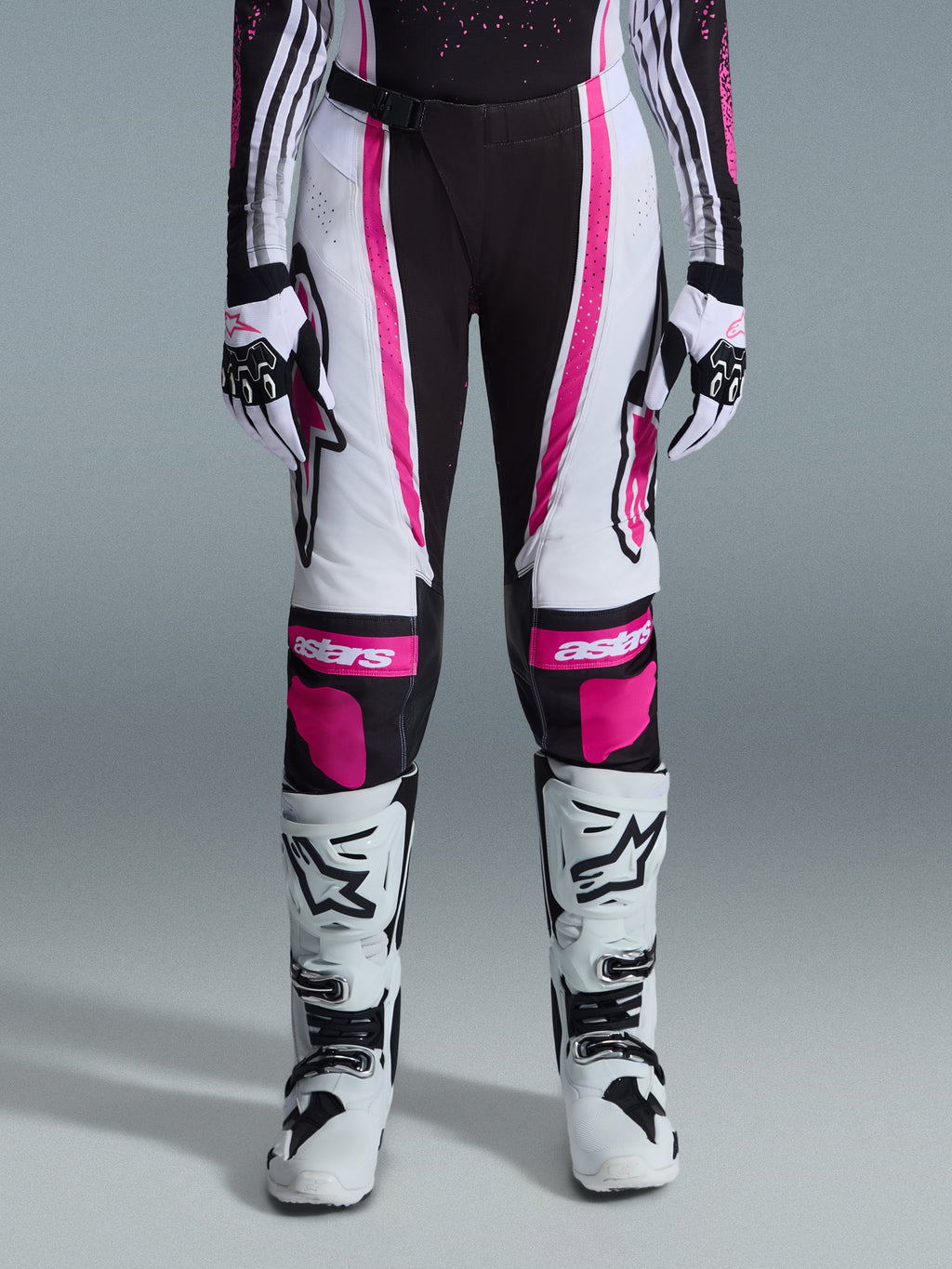 Alpinestars 2026 Stella Techstar Nomur bukser til kvinder, motocross-bukser, sort, hvid og fuchsia, båret med matchende racertrøje, handsker og hvide motocross-støvler, med markant pink grafik og astars-logoer på knæene, designet til off-road-konkurrence på højt niveau