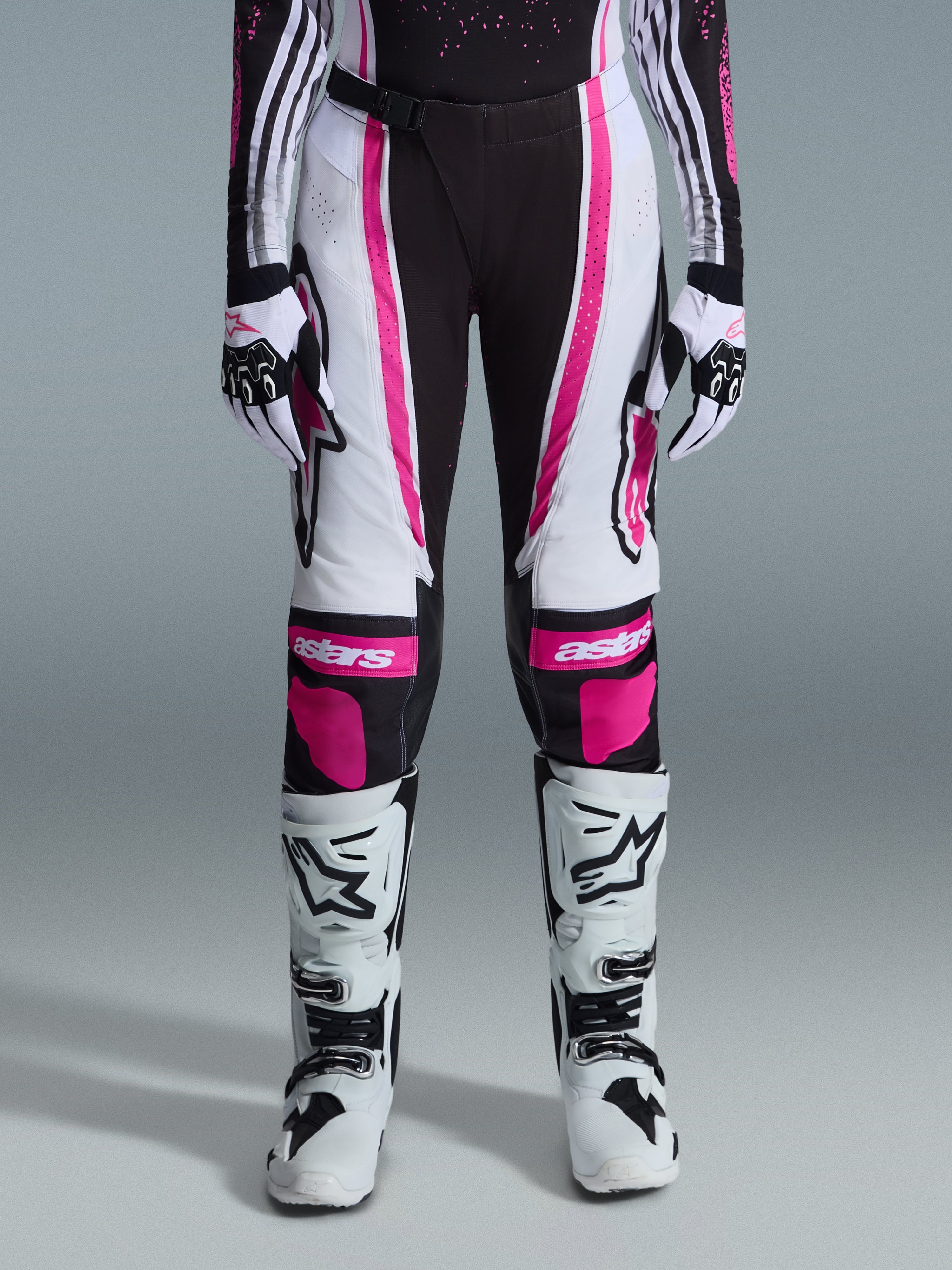 Alpinestars 2026 Stella Techstar Nomur bukser til kvinder, motocross-bukser, sort, hvid og fuchsia, båret med matchende racertrøje, handsker og hvide motocross-støvler, med markant pink grafik og astars-logoer på knæene, designet til off-road-konkurrence på højt niveau