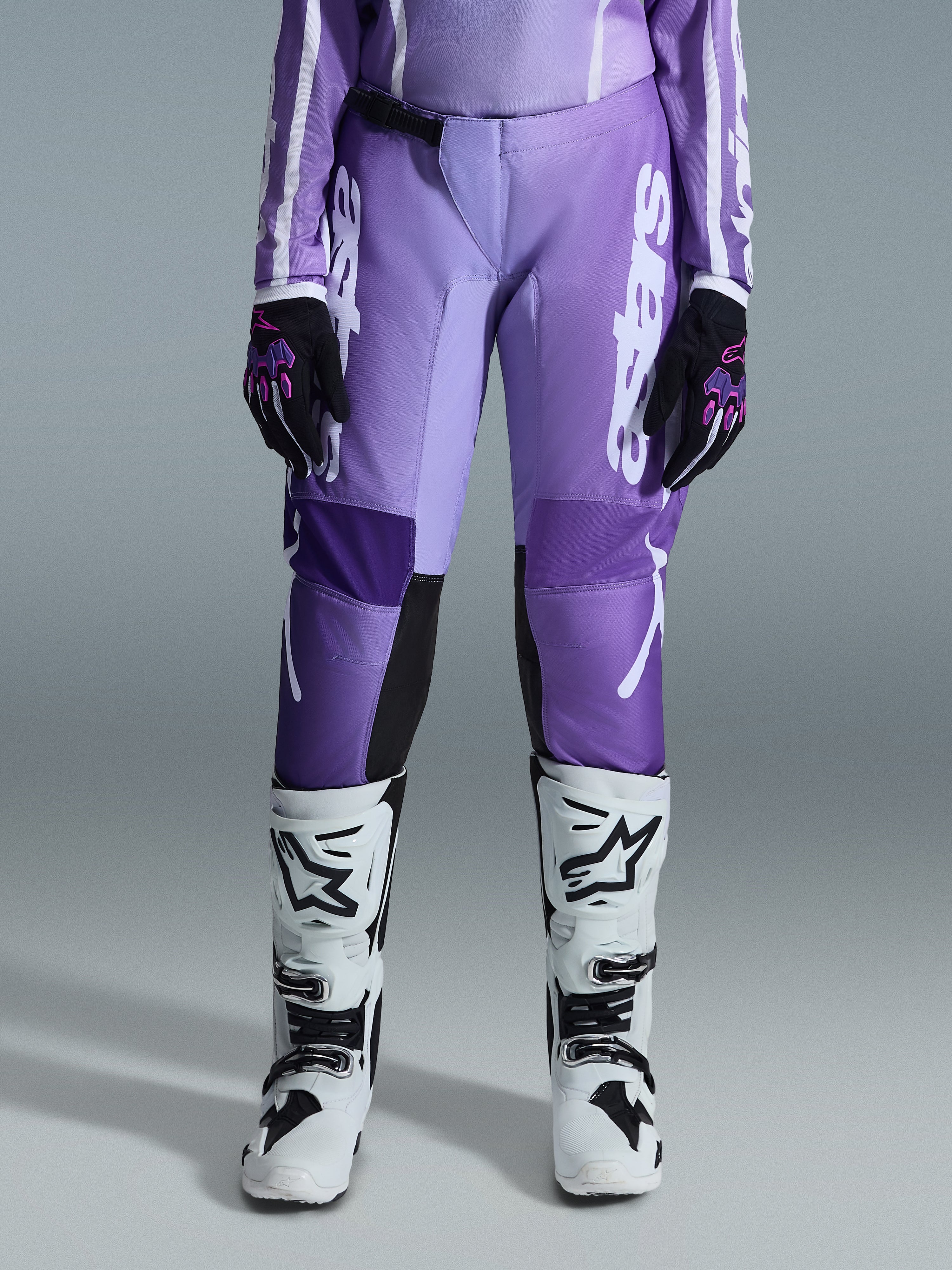 Alpinestars 2026 Stella Fluid Apex bukser til damer, motocross-bukser, violet og hvid, båret med sorte og violette handsker og hvide og sorte støvler, med markant hvid branding på benet, ergonomisk sport-fit design til off-road racing