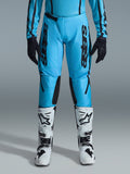 Alpinestars 2026 Stella Fluid Apex bukser til damer, motocrossbukser, klar cyan og sort, lodret sort branding på lårene, sorte forstærkede indvendige knæpaneler, vist med hvide og sorte motocross-støvler og sorte handsker, professionelt off-road-udstyr til kvinder