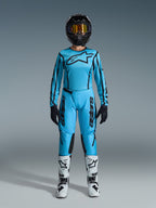 Alpinestars 2026 Stella Fluid Apex-udstyrssæt, motocross-trøje og -bukser til damer, blå og sort, med et stort stjernelogo på brystet, båret med sort hjelm, tonede briller og hvide støvler med sorte detaljer, komplet off-road racingoutfit