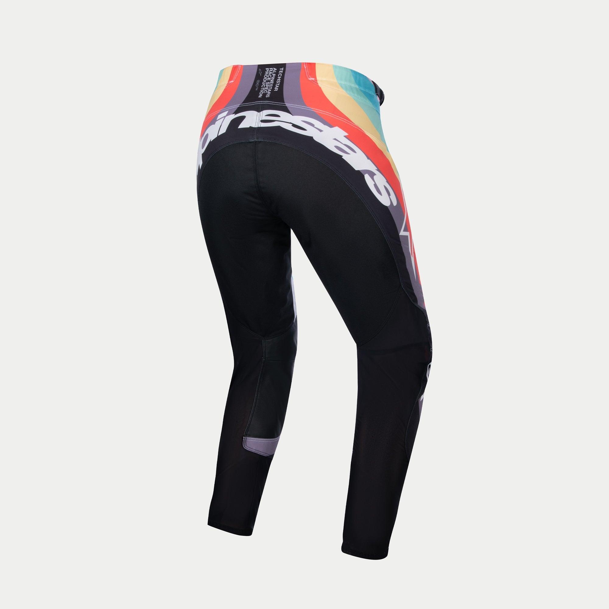 Alpinestars Stella 2024 Techstar bukser til kvinder, motocrossbukser, sort multikolor, set bagfra med et livligt bølgemønster i rød, orange og blå ved taljen, stort hvidt Alpinestars-logo på tværs af bagsiden, designet til off-road racing