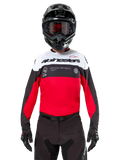 Alpinestars Pro-Dura Jersey, motocross-trøje, sort, klar rød og hvid, vist med sort hjelm og goggles, sporty design med markant Alpinestars-branding og laserperforeringer, performance-udstyr til enduro og off-road racing