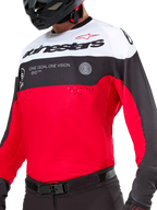 Alpinestars Pro-Dura Jersey, motocross- og enduro-trøje, sort, klar rød og hvid, med 'ONE GOAL. ONE VISION.'-grafik og laserperforeringer på brystet, båret med sorte motocross-bukser og hjelm.