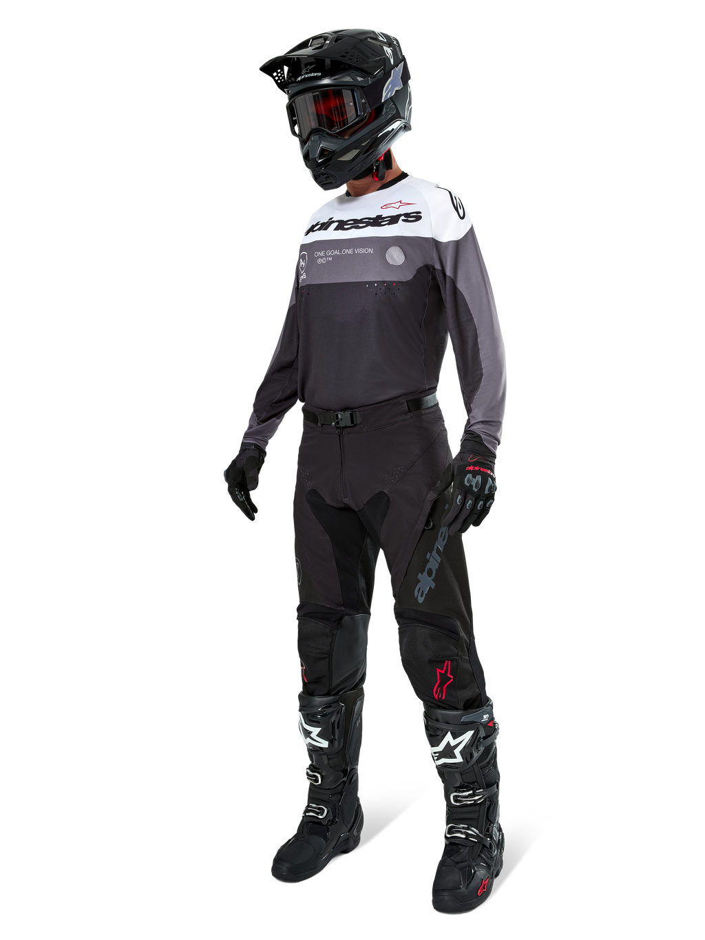 Alpinestars Pro-Dura Jersey i Black Magnet White, båret af en motocross-kører i fuldt gear, inklusive sorte bukser, sort hjelm med goggles og sort-hvide støvler. Jerseyen har et teknisk farveopdelt design med hvide, grå og sorte paneler, skabt til enduro- og off-road-performance.