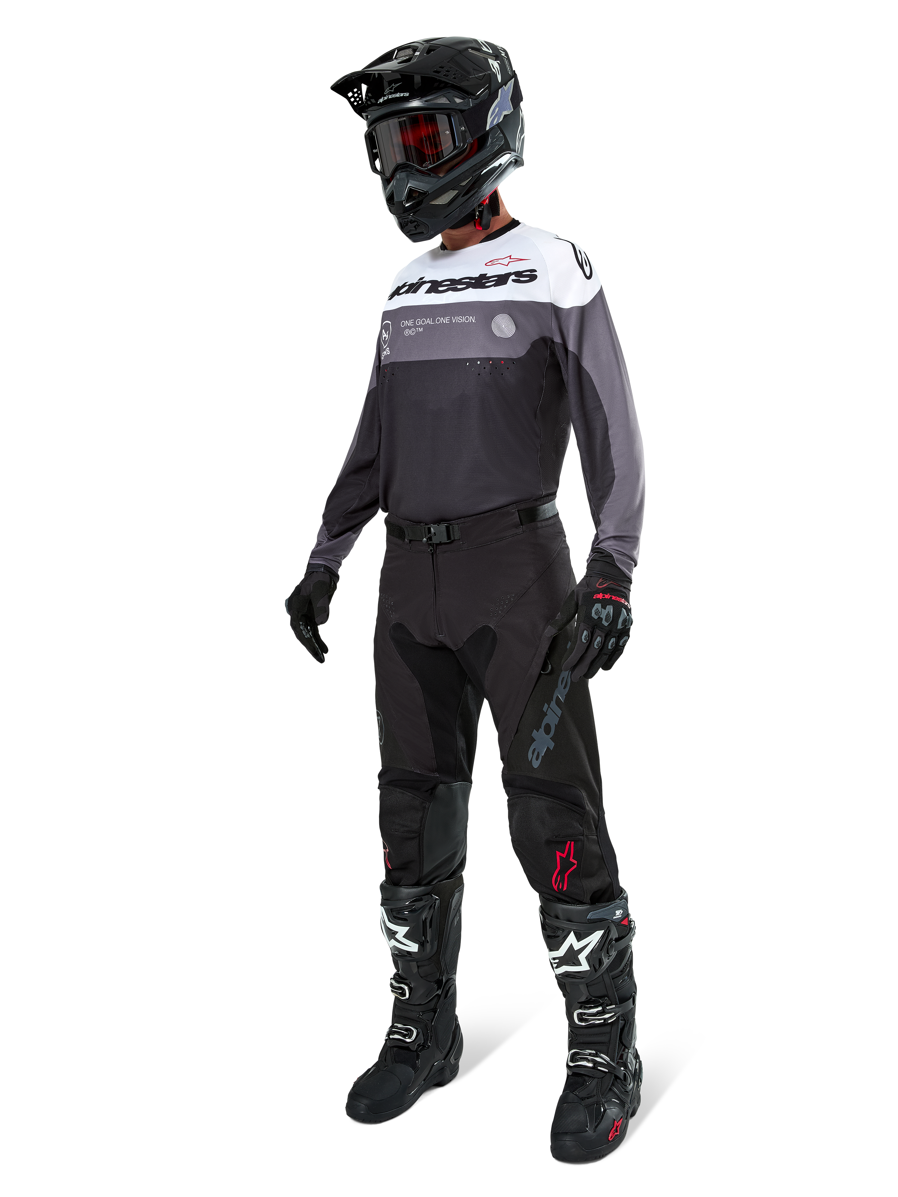 Alpinestars Pro-Dura Jersey i Black Magnet White, båret af en motocross-kører i fuldt gear, inklusive sorte bukser, sort hjelm med goggles og sort-hvide støvler. Jerseyen har et teknisk farveopdelt design med hvide, grå og sorte paneler, skabt til enduro- og off-road-performance.