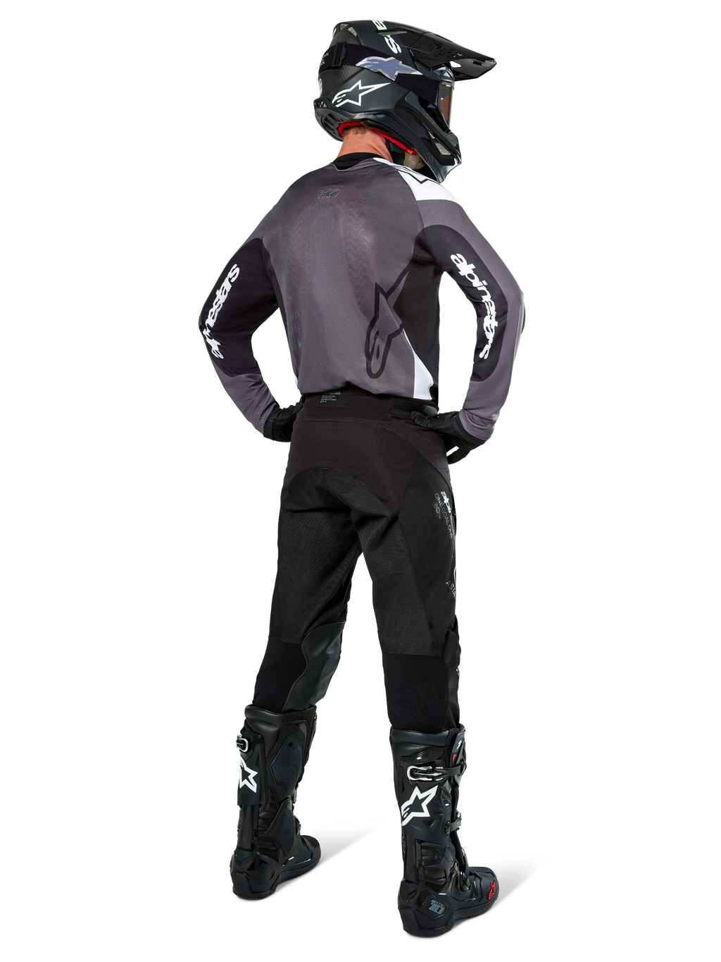 Motocross-kører iført Alpinestars Pro-Dura Jersey i Black Magnet White, set bagfra med gråt mesh-rygpanel og sorte ærmer med hvid Alpinestars-branding, koordineret med sorte bukser, sort hjelm og sort-hvide støvler, professionelt enduro-racerudstyr