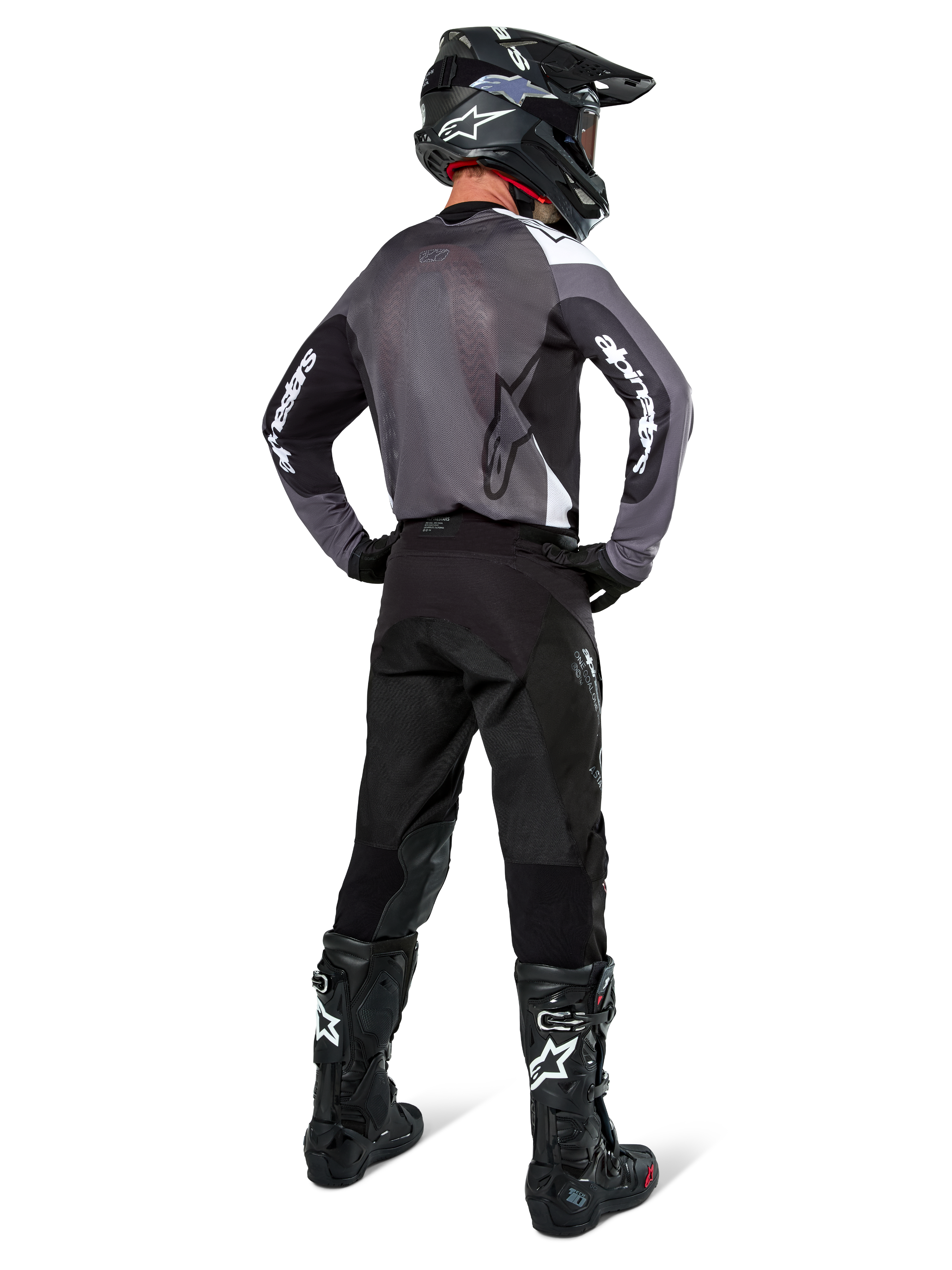 Motocross-kører iført Alpinestars Pro-Dura Jersey i Black Magnet White, set bagfra med gråt mesh-rygpanel og sorte ærmer med hvid Alpinestars-branding, koordineret med sorte bukser, sort hjelm og sort-hvide støvler, professionelt enduro-racerudstyr