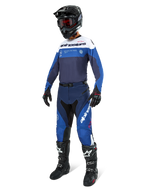 Motocross-kører i komplet racerudstyr, Pro-Dura Jersey i Navy Bright Blue og hvid, matchende blå og navy bukser, sort hjelm med røde goggles, sorte støvler med hvide detaljer og sorte handsker, koordineret outfit til enduro- og off-road-kørsel
