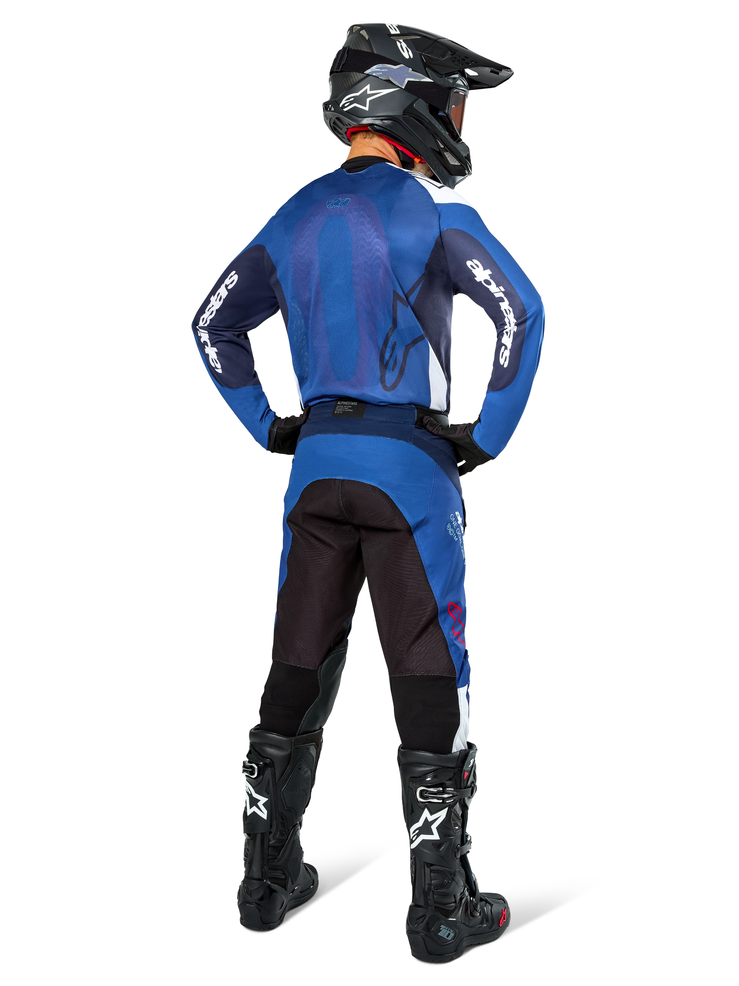 Motocrossrytter set bagfra iført Alpinestars Pro-Dura trøje i navy og klar blå, matchende blå og sorte bukser, sort motocrosshjelm med goggles og sorte støvler, der viser et koordineret off-road racersæt