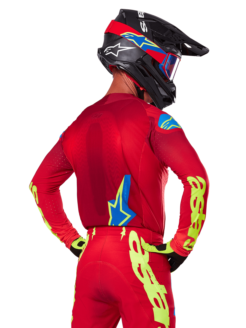 Bagfra af en motocrosskører iført Alpinestars 2025 Supertech Maker-udstyrssæt i rød, bestående af en rød jersey med neongul branding på ærmerne, matchende røde bukser, en sort hjelm med blå og røde detaljer samt koordinerende sorte og gule handsker.