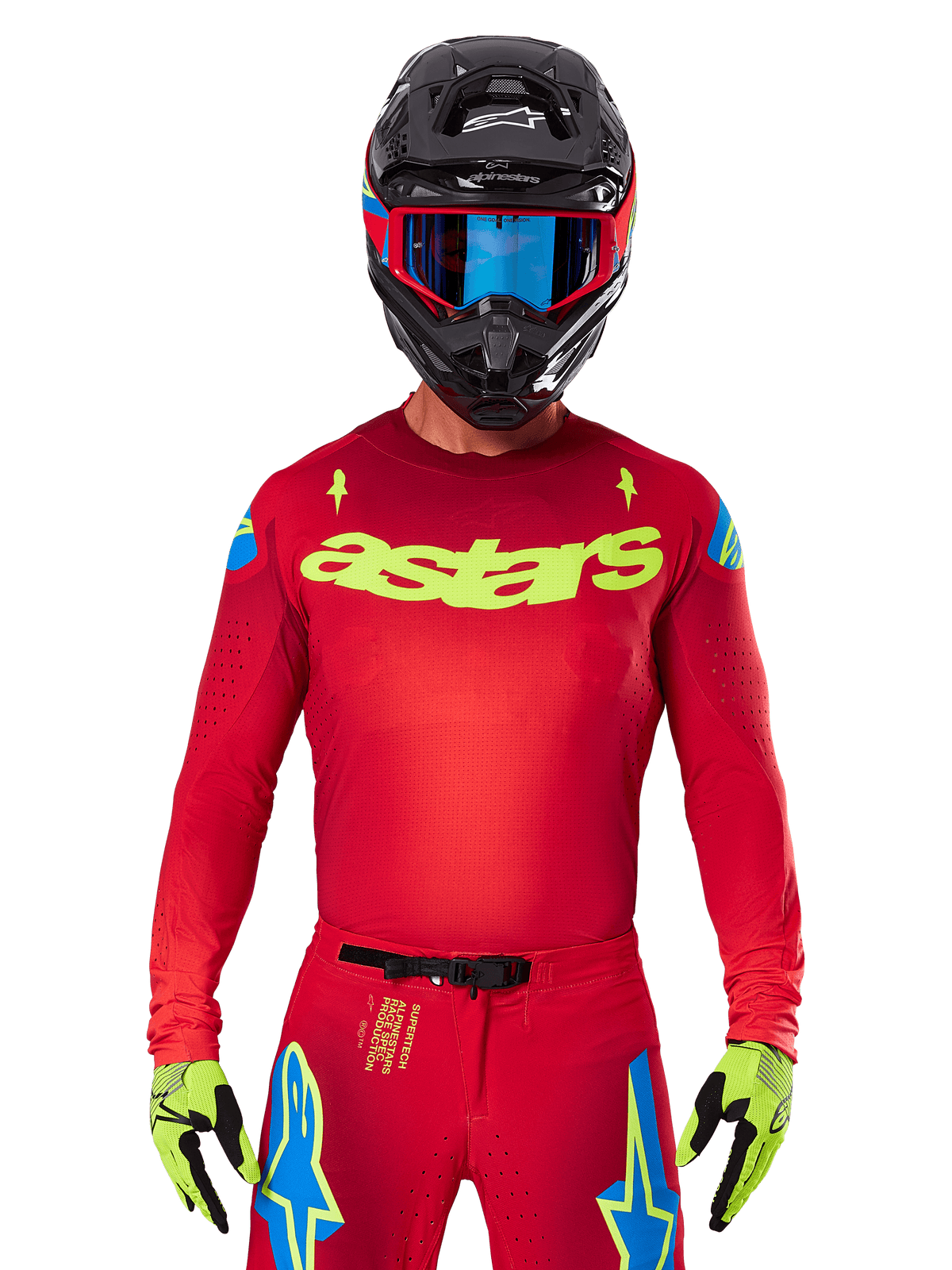Alpinestars 2025 Supertech Maker Jersey i Bright Red Yellow Fluo, med gult 'astars' brystlogo og blå stjernedesigns på skuldrene, båret med matchende bukser, sort hjelm, blå goggles og gule handsker, professionelt motocross-racerudstyr