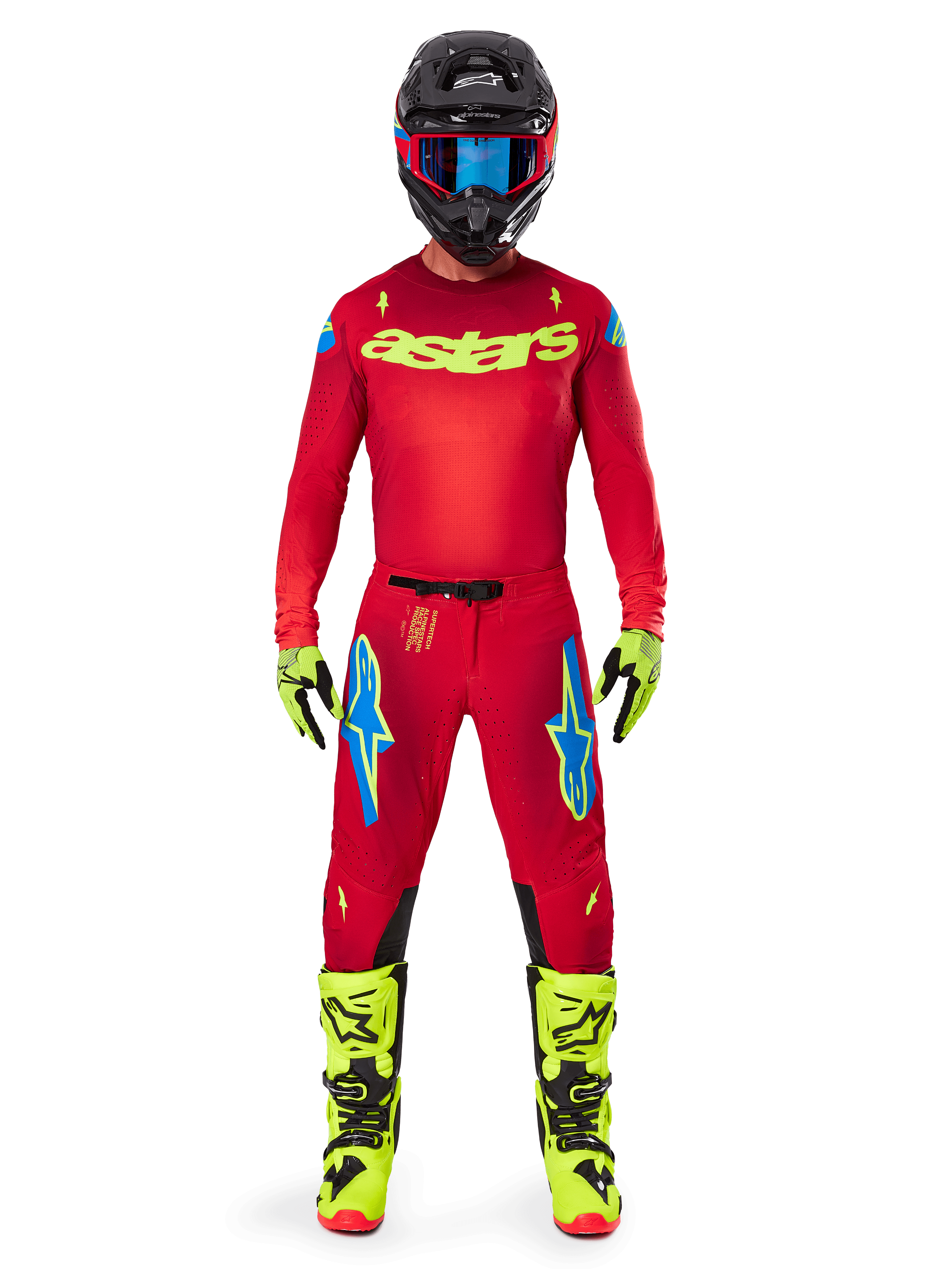 Motocross-kører iført Alpinestars 2025 Supertech Maker Jersey og matchende bukser i Bright Red og Yellow Fluo, med gult 'astars'-logo på brystet, sort hjelm med blå goggles, neon-gule handsker og støvler, komplet professionelt racer-outfit til terrænkørsel.