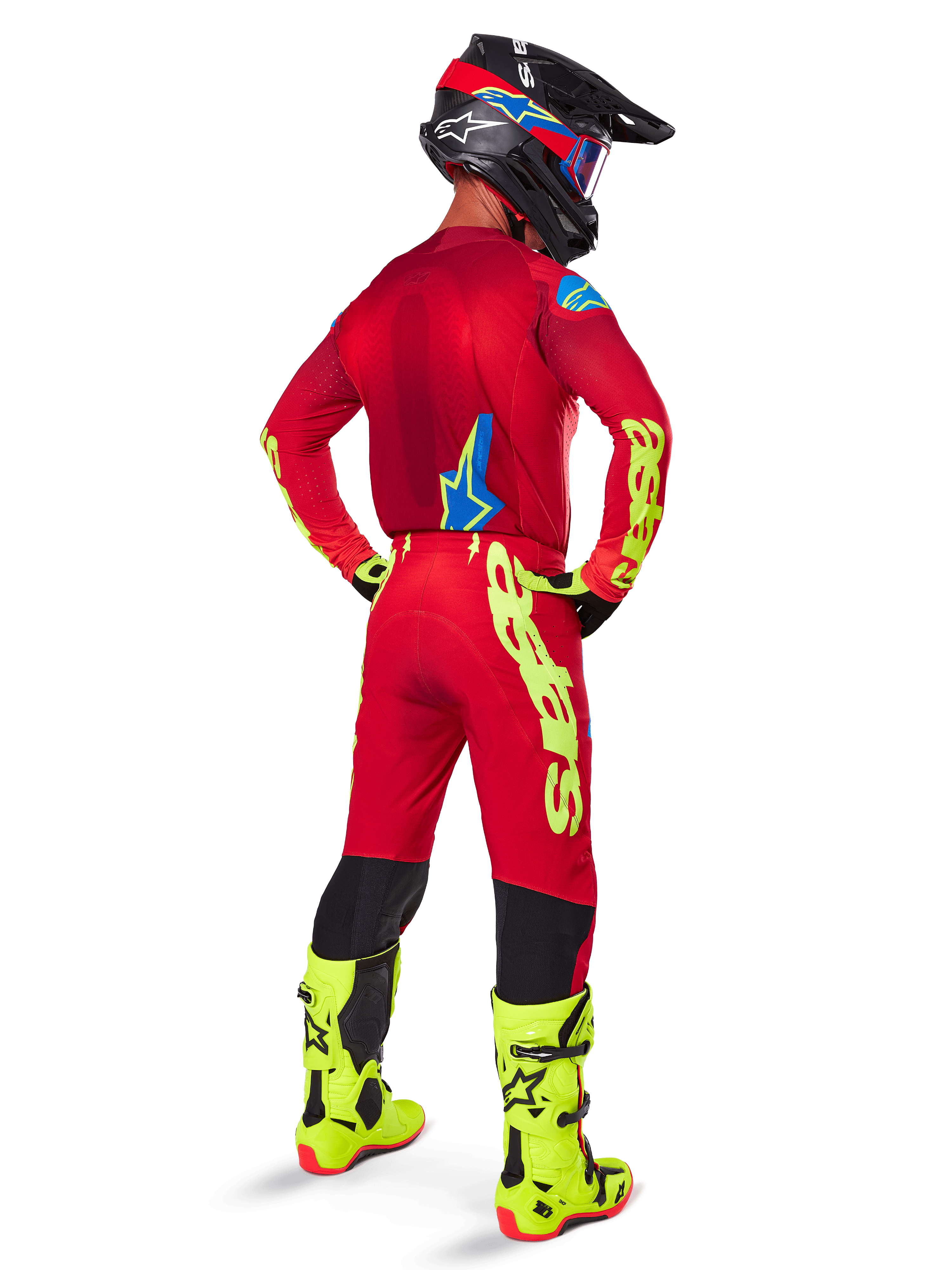 Motocrosskører set bagfra iført Alpinestars 2025 Supertech Maker Jersey, Bright Red og Yellow Fluo, matchende bukser med gul branding, neon-gule støvler og en sort og rød hjelm, koordineret sæt til off-road racing på professionelt niveau