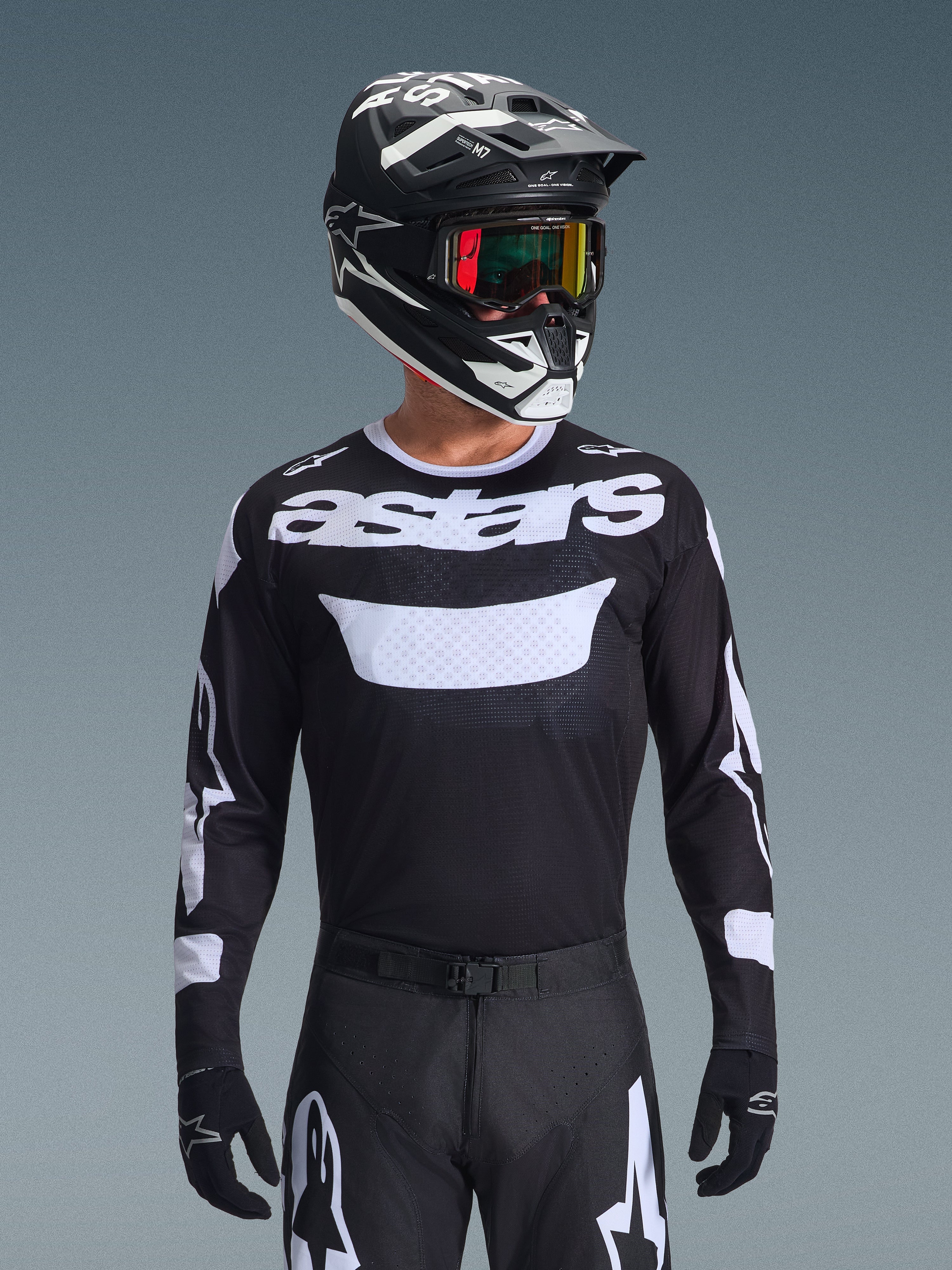 Alpinestars 2026 Racer Air Riway jersey, sort og hvid motocross-trøje med 'astars'-branding, båret af en kører med matchende sort hjelm, goggles og bukser, med åndbare mesh-paneler til off-road racing.