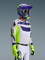 Motocross-rytter iført Alpinestars 2026 Racer Air Riway-trøje, lysegrå med fluo-gule og blå detaljer, kombineret med en matchende blå og gul hjelm og fluo-gule handsker, med åndbar mesh-konstruktion og professionel racer-styling til off-road ydeevne.