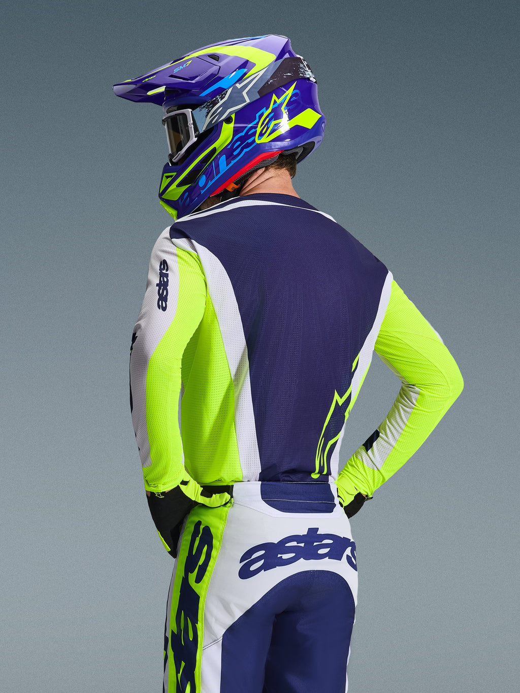 Alpinestars 2026 Racer Air Riway trøje, motocross-trøje, lys grå, gul fluo og blå, rygbillede af kører iført matchende bukser og hjelm, atletisk race-pasform med åndbare mesh-paneler til off-road racing