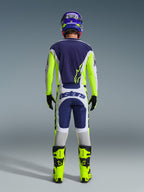 Bagsidevisning af en motocrosskører iført Alpinestars 2026 Racer Air Riway-trøje og matchende bukser i Light Gray Yellow Fluo Blue, kombineret med neongule støvler og en matchende hjelm, som viser et komplet off-road racersæt.