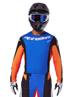 Alpinestars 2025 Techstar Melt Jersey, Motocross Jersey, Blue and Orange with black side panels, worn with black helmet and blue goggles, featuring breathable laser-cut perforations on chest, athletic race fit for off-road performance
