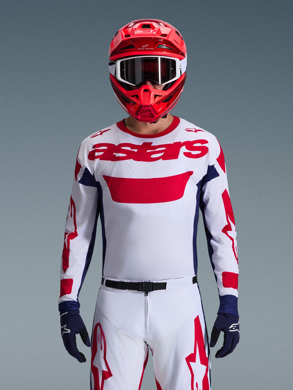 Alpinestars 2026 Racer Riway Gear Set, motocross-kører iført hvid trøje med rød branding og mørkeblå detaljer, matchende hvide bukser med rød grafik, rød hjelm med hvide goggles, mørkeblå handsker, professionelt koordineret terrænkørselsudstyr.