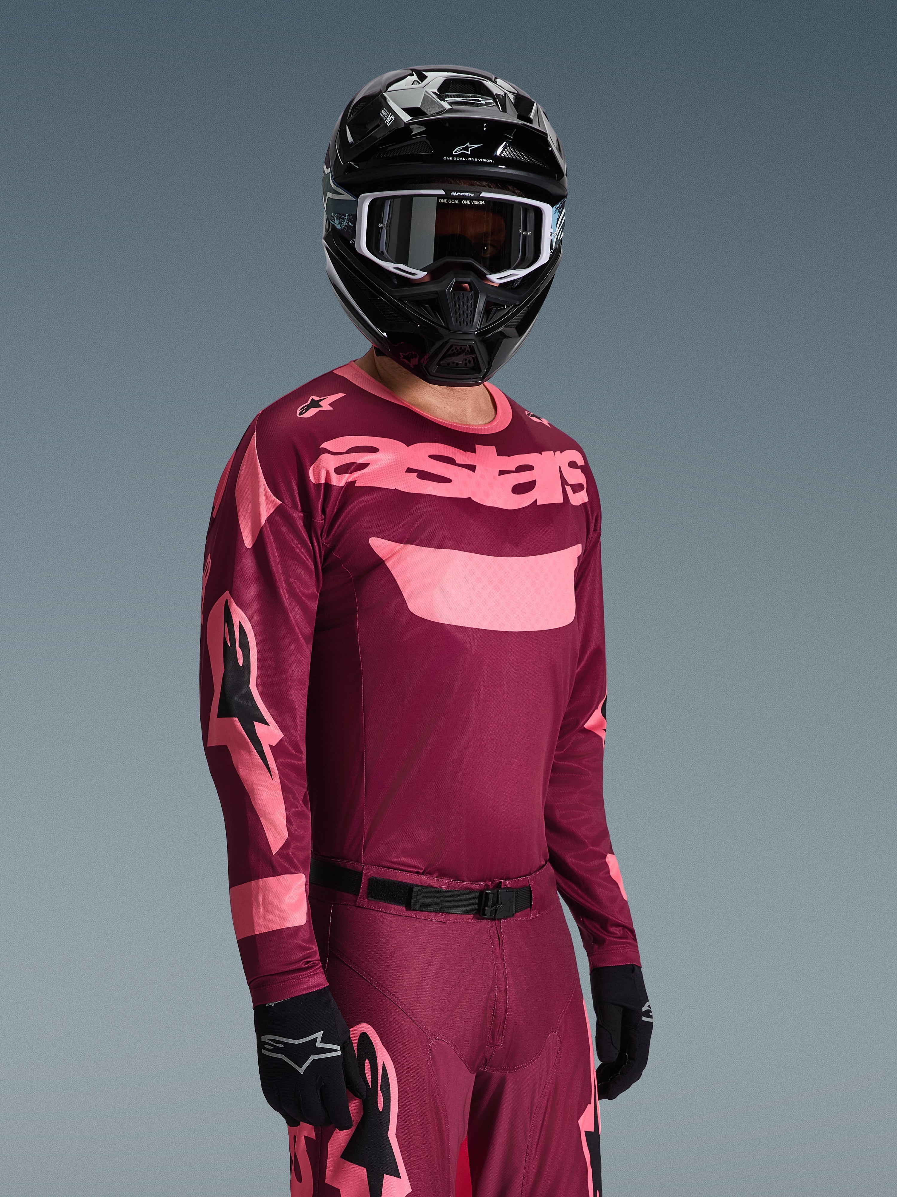 Alpinestars 2026 Racer Riway Gear Set, motocrosskører iført bordeaux og lyserød jersey med tydelig 'astars'-branding, matchende bukser med lyserøde detaljer, sort hjelm og handsker, professionelt raceroutfit til off-road motocross