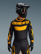 Alpinestars 2026 Racer Riway Gear Set, motocross-kører iført sort jersey med markant gult 'astars' logo, matchende sorte bukser med gule detaljer, sort hjelm og goggles, sorte handsker, professionelt udstyr til terrænkørsel