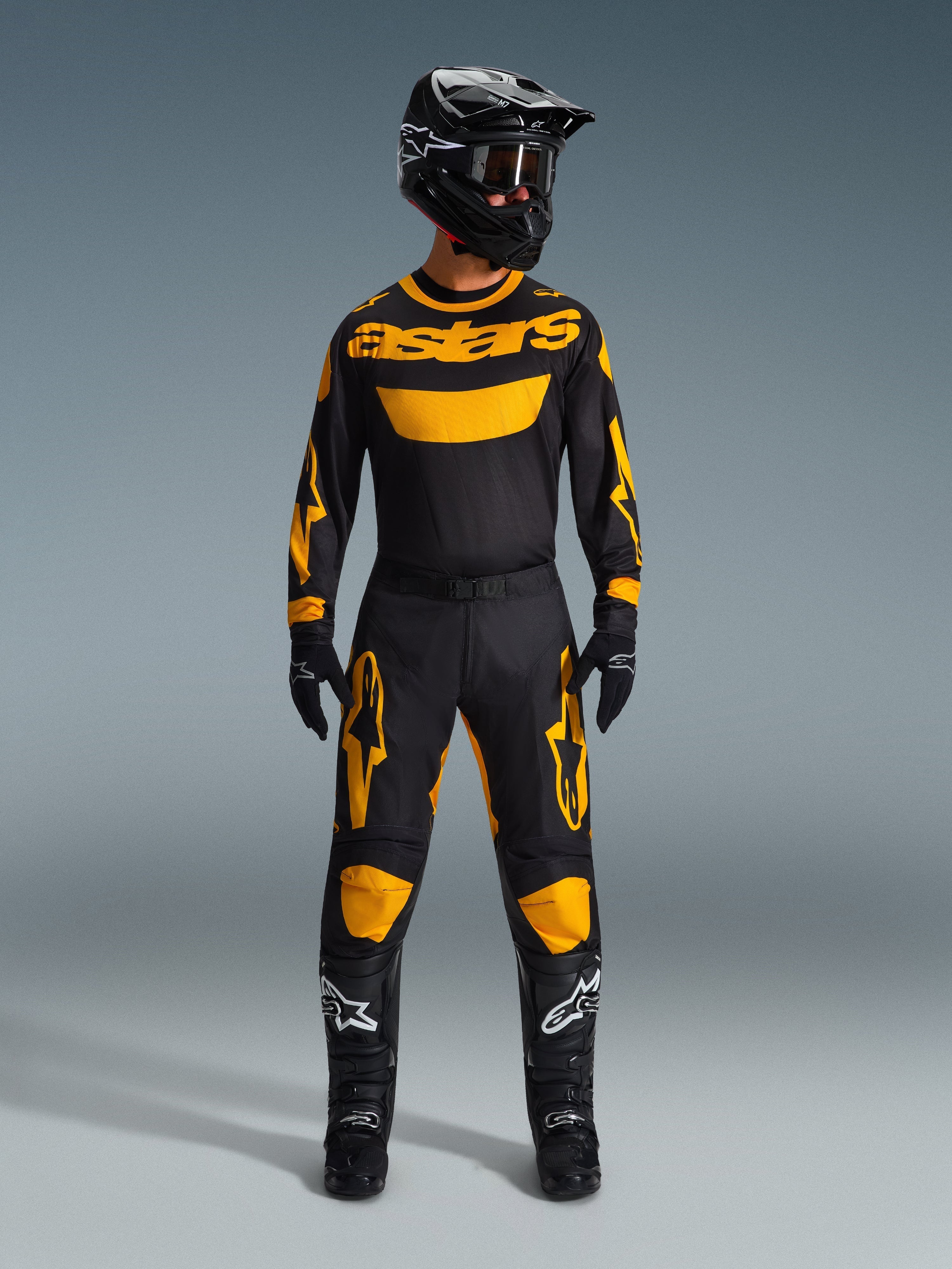 Motocross-rytter iført 2026 Racer Riway Jersey i gul og sort, matchet med tilhørende bukser, sort hjelm og sorte støvler med hvide Alpinestars-logoer, komplet udstyrssæt til off-road racing.