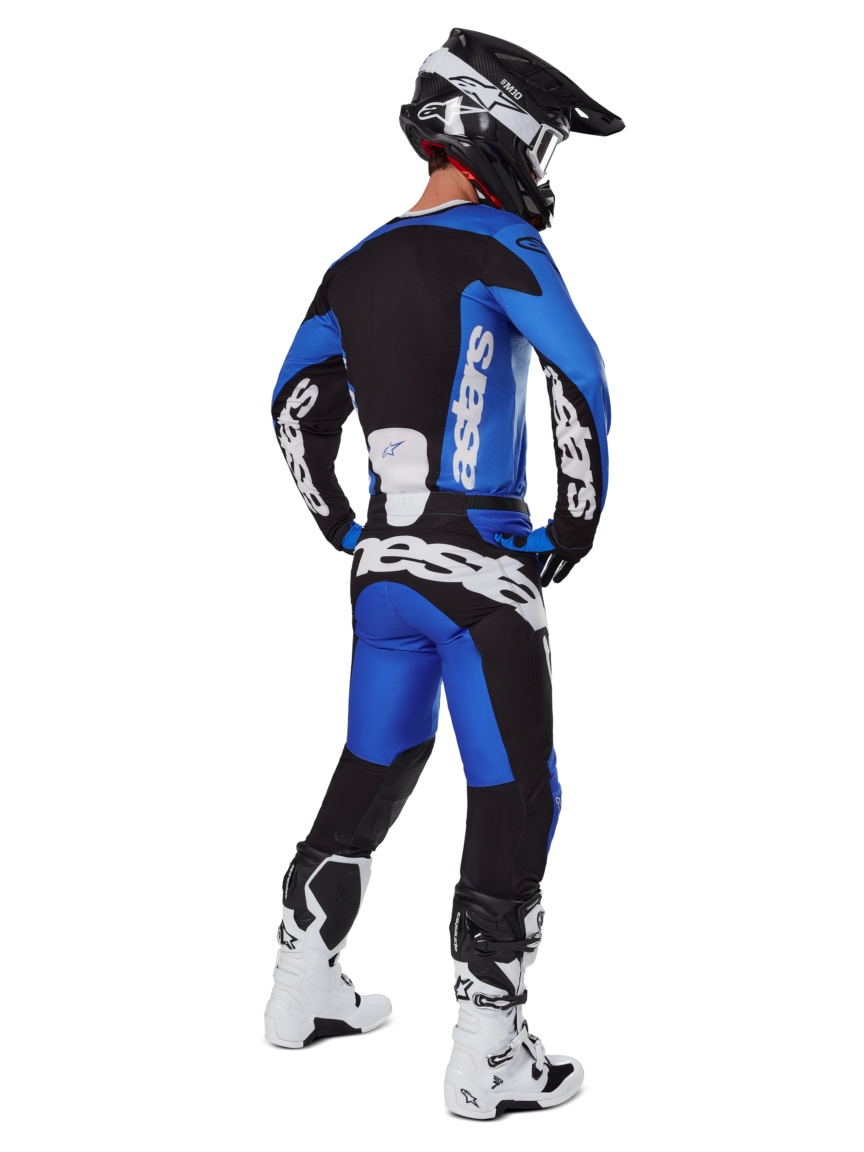 Motocross rider wearing complete racing gear seen from behind, 2025 Racer Veil Jersey and matching pants in Blue and Black, featuring white Alpinestars branding, black helmet, white and black boots, coordinated outfit for off-road racing