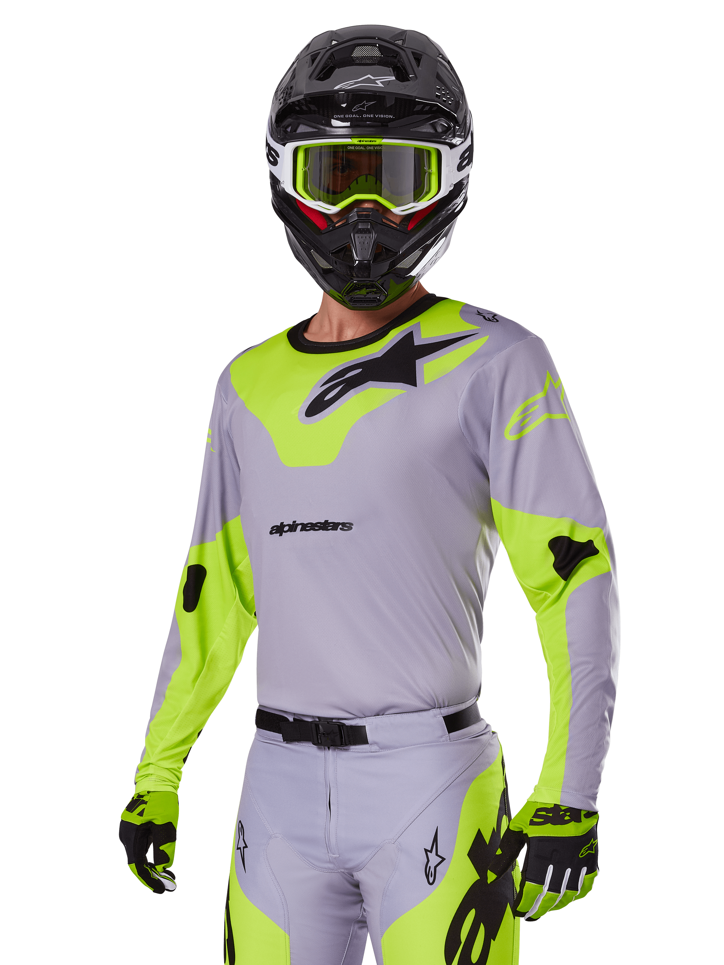 Alpinestars 2025 Racer Veil Gear Set, motocrosskører iført gråt og neongrønt udstyrssæt, lysegrå trøje og bukser med markante neongule paneler og sorte logoer, koordineret med matchende handsker og sort hjelm med neongrønne goggles, professionelt udstyr til terrænkørsel.