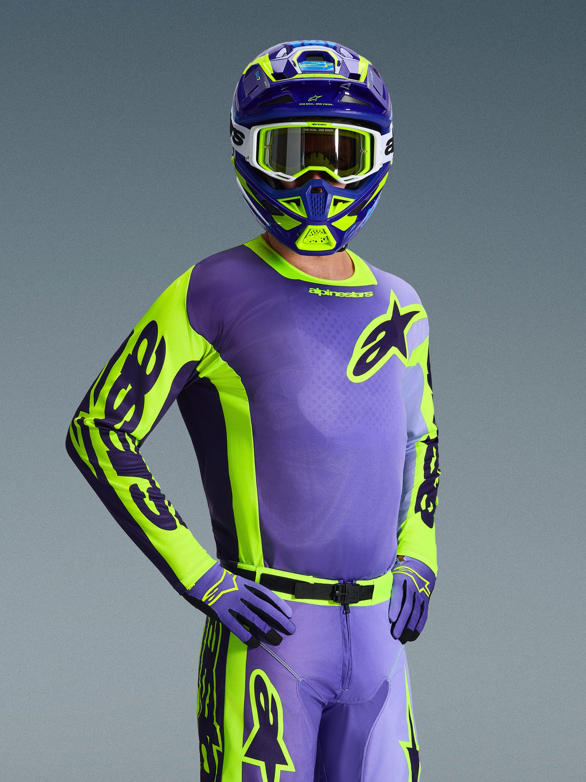 Motocross-kører iført 2026 Racer Portl-trøje, lilla og neongul, matchende lilla og gul hjelm med hvide goggles, lilla og gule handsker, koordineret komplet udstyrssæt til terrænkørsel