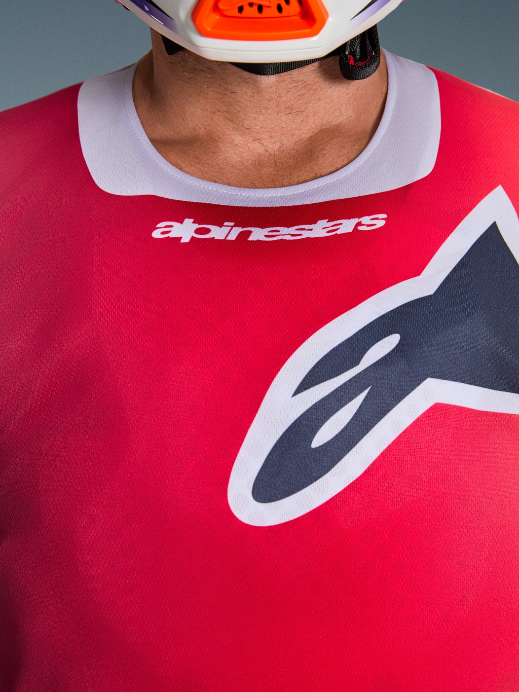 Alpinestars 2026 Racer Portl Jersey, nærbillede af bryst- og kraveområdet, rød med lysegrå halskant, hvid Alpinestars-tekst og stort Astars-logo, med en fugttransporterende teknisk tekstur